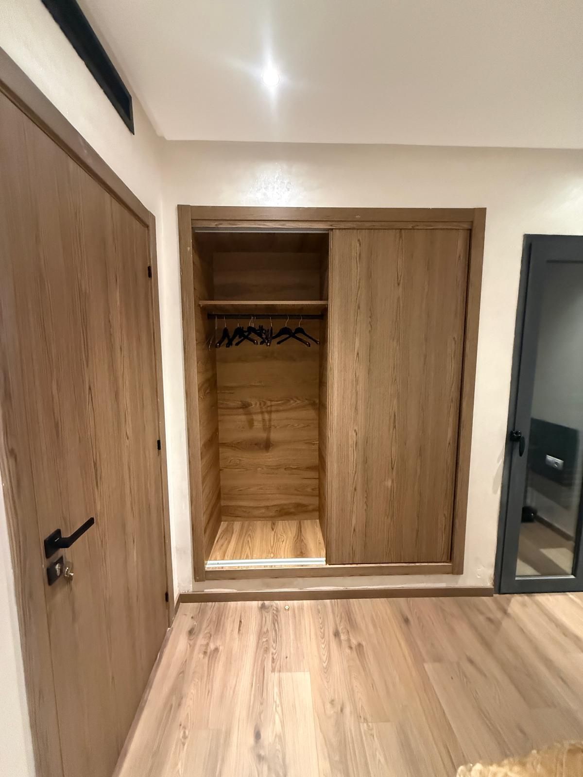 Une pièce avec une armoire en bois, une porte et un miroir.