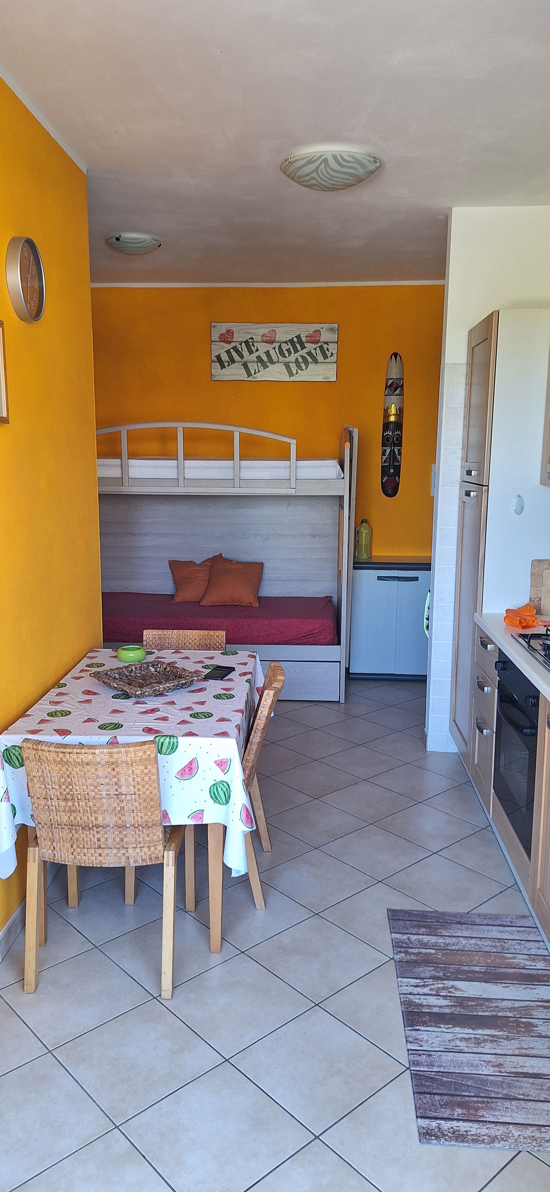 A compact living space with a dining area, kitchenette, and a bed with a headboard.
