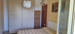 A bedroom with a bed, a wardrobe, a door, and a wall-mounted air conditioner.