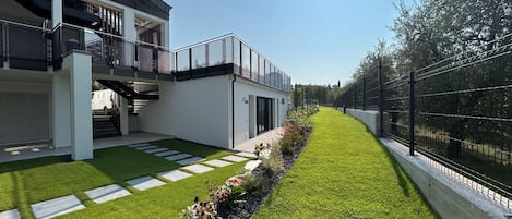 A modern building with a flat roof, a balcony, and a well-maintained lawn with stepping stones.