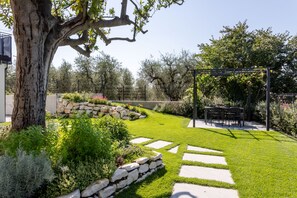 A landscaped garden with a stone wall, a pergola, and a seating area. - Rebo apartment in Puegnago del Garda with pool (Puegnago sul Garda)