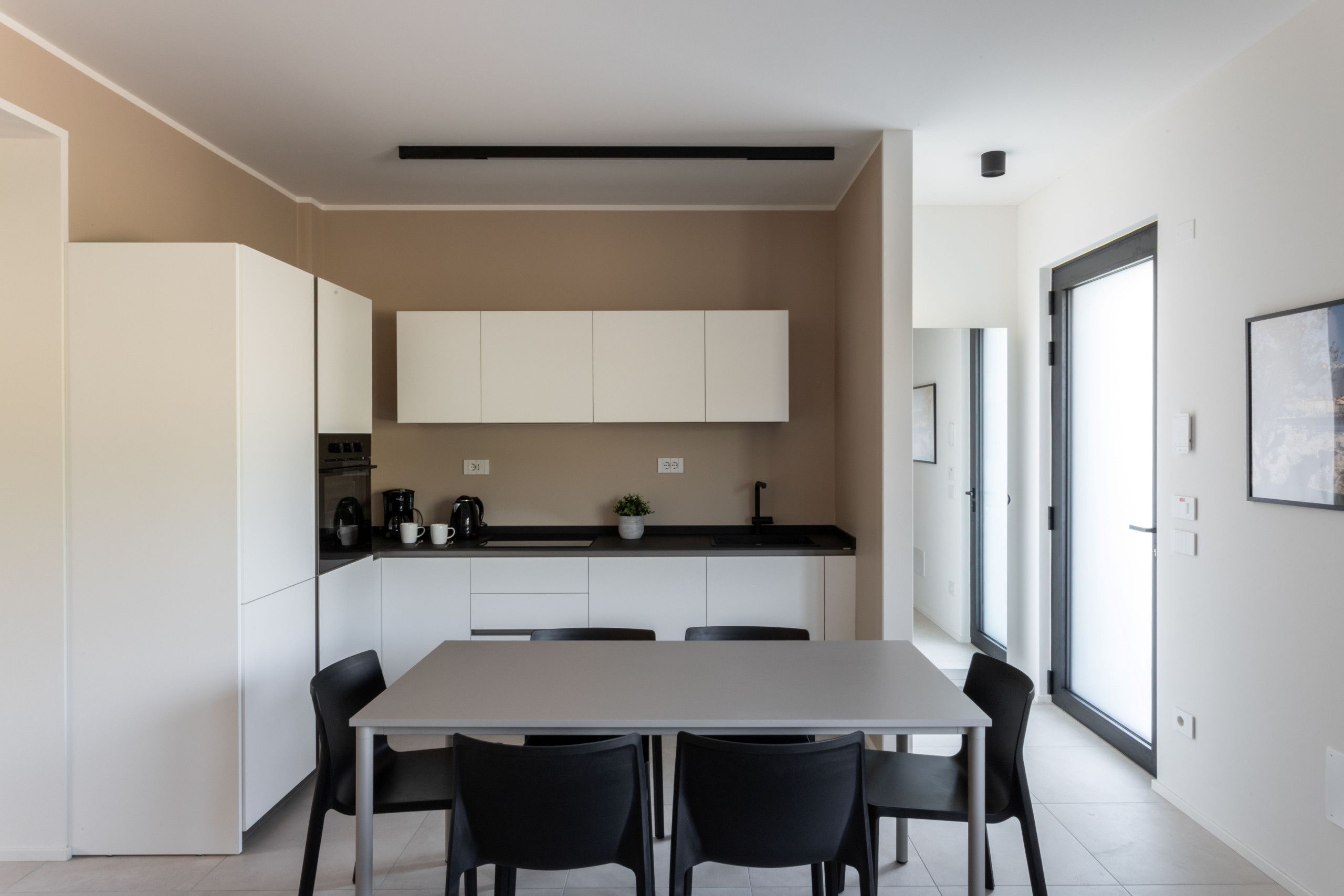 A modern kitchen with white cabinets, a black countertop, and a dining area with a table and chairs.