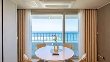 A hotel room with a balcony, a round table, and a view of the beach.
