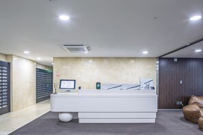 A reception area with a white reception desk, a computer monitor, and a glass display case.