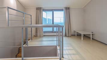 A room with a bunk bed, a desk, and a window with curtains.