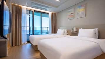 A hotel room with two beds, a TV, and a balcony with curtains.