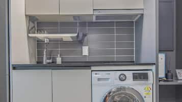 A compact laundry room with a washing machine, cabinets, and a tiled backsplash.