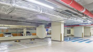 A parking garage with multiple levels, marked parking spaces, and visible structural elements like beams and columns.
