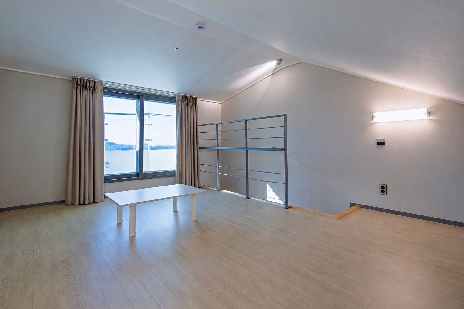 A room with a large window, a table, and a metal partition.