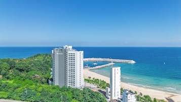 A coastal cityscape with high-rise buildings, a beach, and a clear blue sky.
