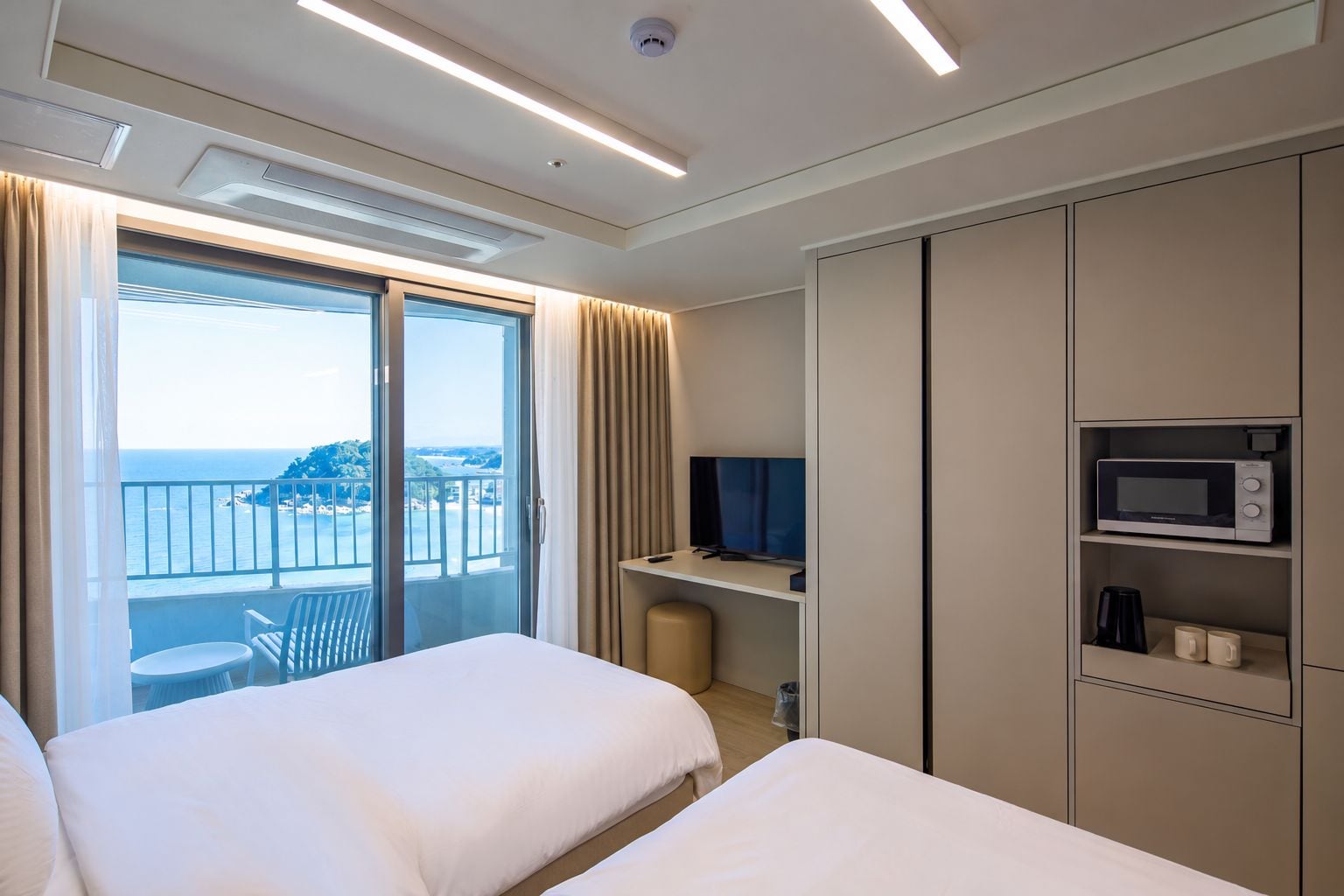 A hotel room with a balcony, a bed, a TV, a microwave, and a coffee maker.