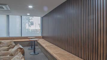 A waiting area with a long bench, two round tables, and a wooden slatted wall.
