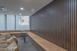 A waiting area with a long bench, two round tables, and a wooden slatted wall.