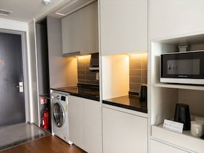 Una cocina moderna con lavadora integrada, microondas y cafetera sobre la encimera.