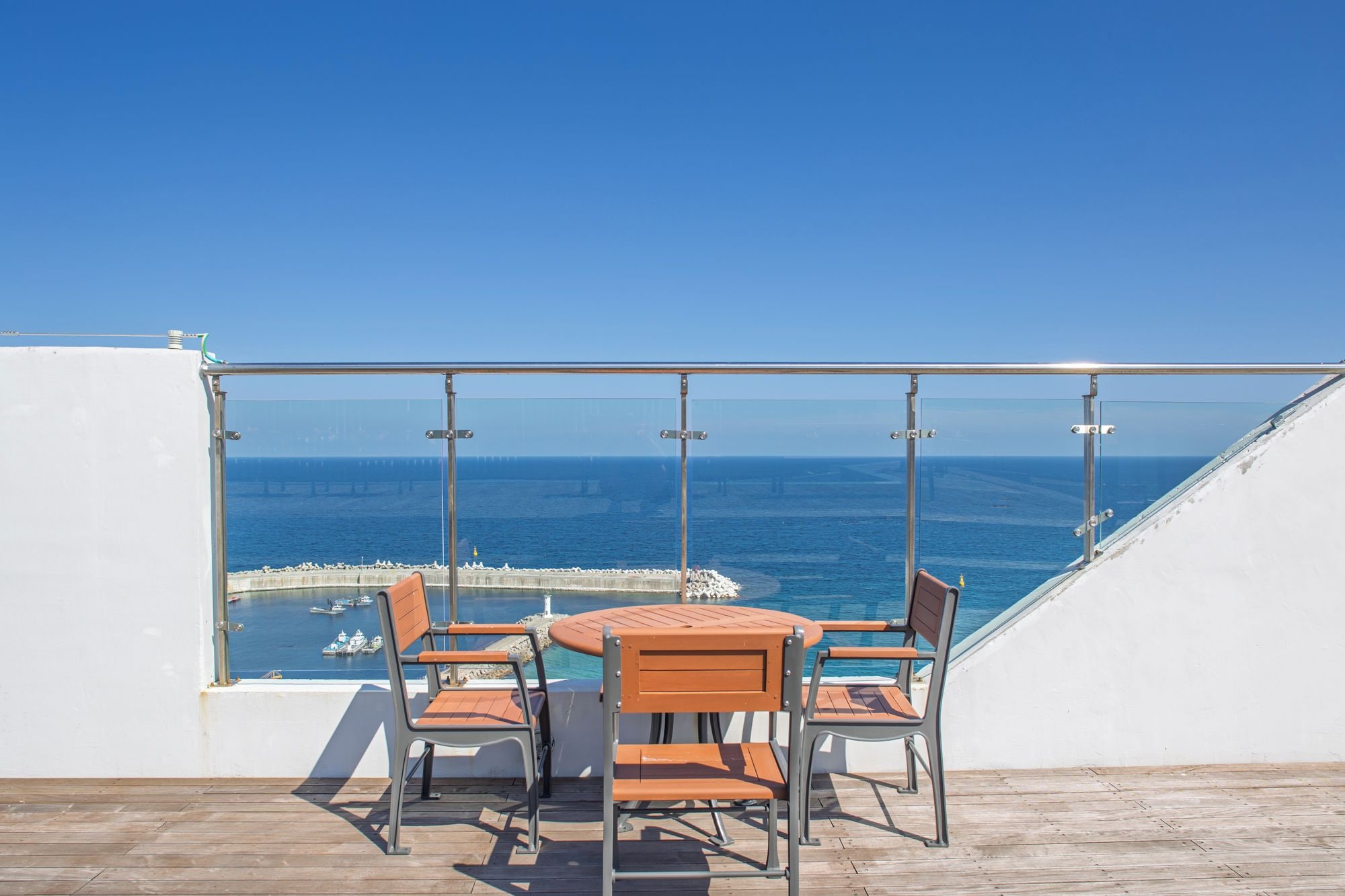 A balcony with a glass railing overlooking a body of water and a pier.