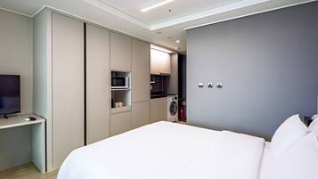 Habitación de hotel moderna con cama, televisor, microondas y lavadora.