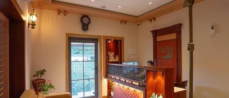 A reception area with a wooden reception desk, a clock, and a ceiling fan.
