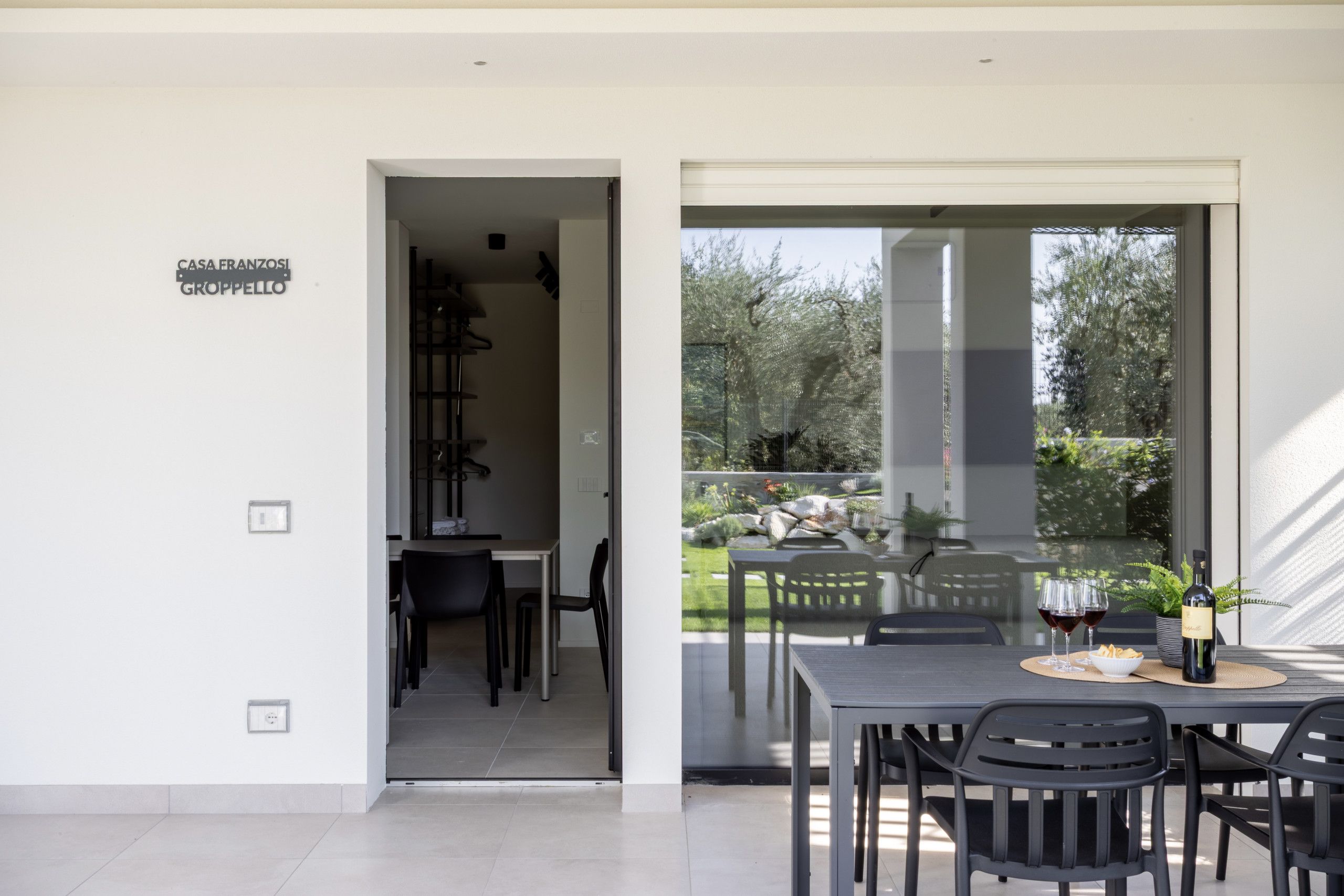 Un coin repas avec une table et des chaises, une vue sur un jardin par une porte vitrée et un panneau indiquant l’emplacement.