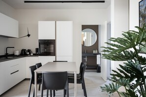 A modern kitchen with white cabinets, a dining table with chairs, and a large mirror. - Apartment Groppello Casa Franzosiwith pool (Puegnago sul Garda)
