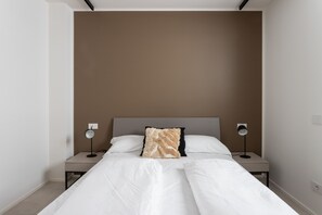 Una camera da letto moderna con un letto grande, due comodini e due lampade a parete.
