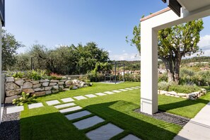 A well-maintained garden with a stone wall, stepping stones, and a variety of plants. - Apartment Groppello Casa Franzosiwith pool (Puegnago sul Garda)