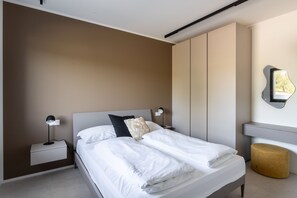A modern bedroom with a bed, bedside tables, and a wall-mounted light fixture. - Apartment Groppello Casa Franzosiwith pool (Puegnago sul Garda)