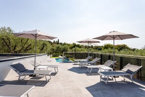 Una terrazza sul tetto con posti a sedere all'aperto, ombrelloni e una piscina.