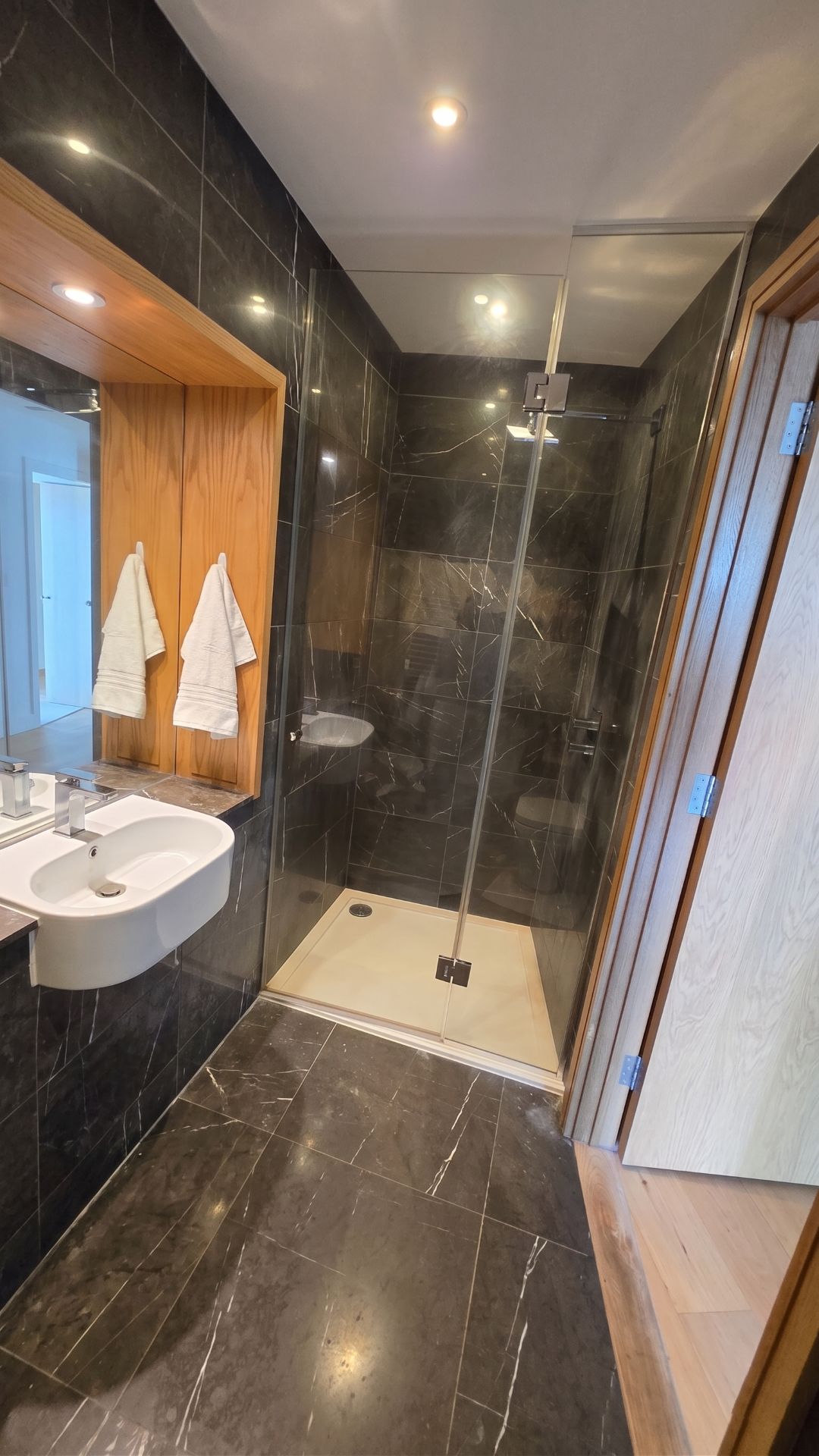 A modern bathroom with a vanity, a shower, and a glass door.
