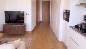 En modern lägenhet med vardagsrum, TV, soffa, kök och hall.
