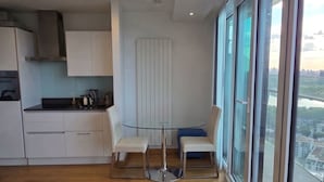 Ett modernt kök med vita skåp, en köksö och en matplats med två stolar.