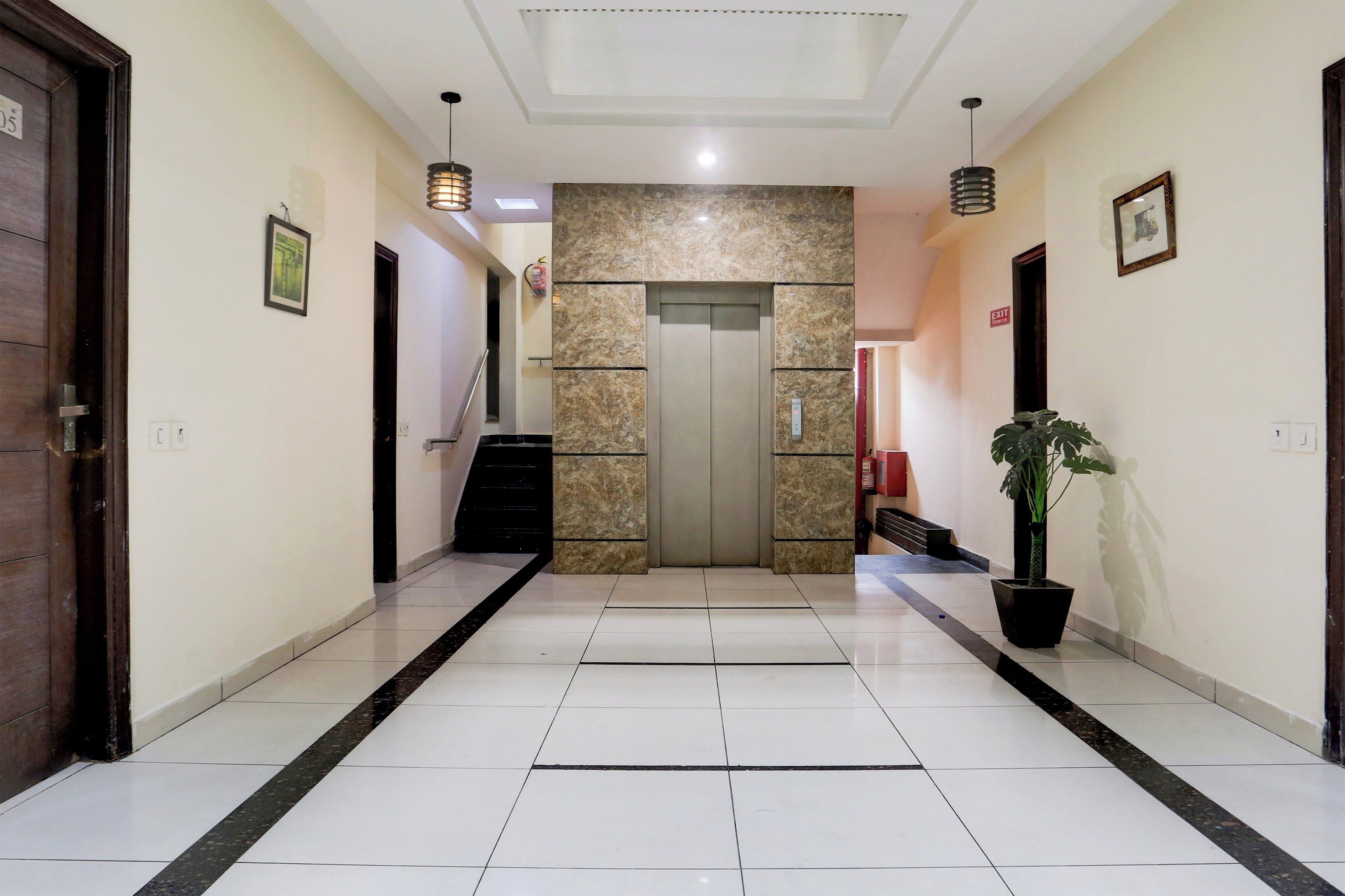 Un vestíbulo de hotel con una pared de mármol, un mostrador de recepción y una planta en maceta.