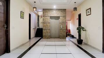 Un vestíbulo de hotel con una pared de mármol, un mostrador de recepción y una planta en maceta.