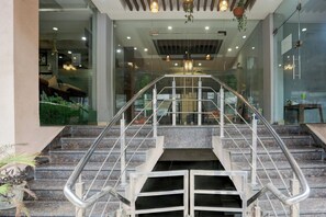 A staircase with metal railings leading to an upper floor, surrounded by glass walls and a ceiling with recessed lighting. - Collection O by OYO Railway Station Road (Ludhiana)