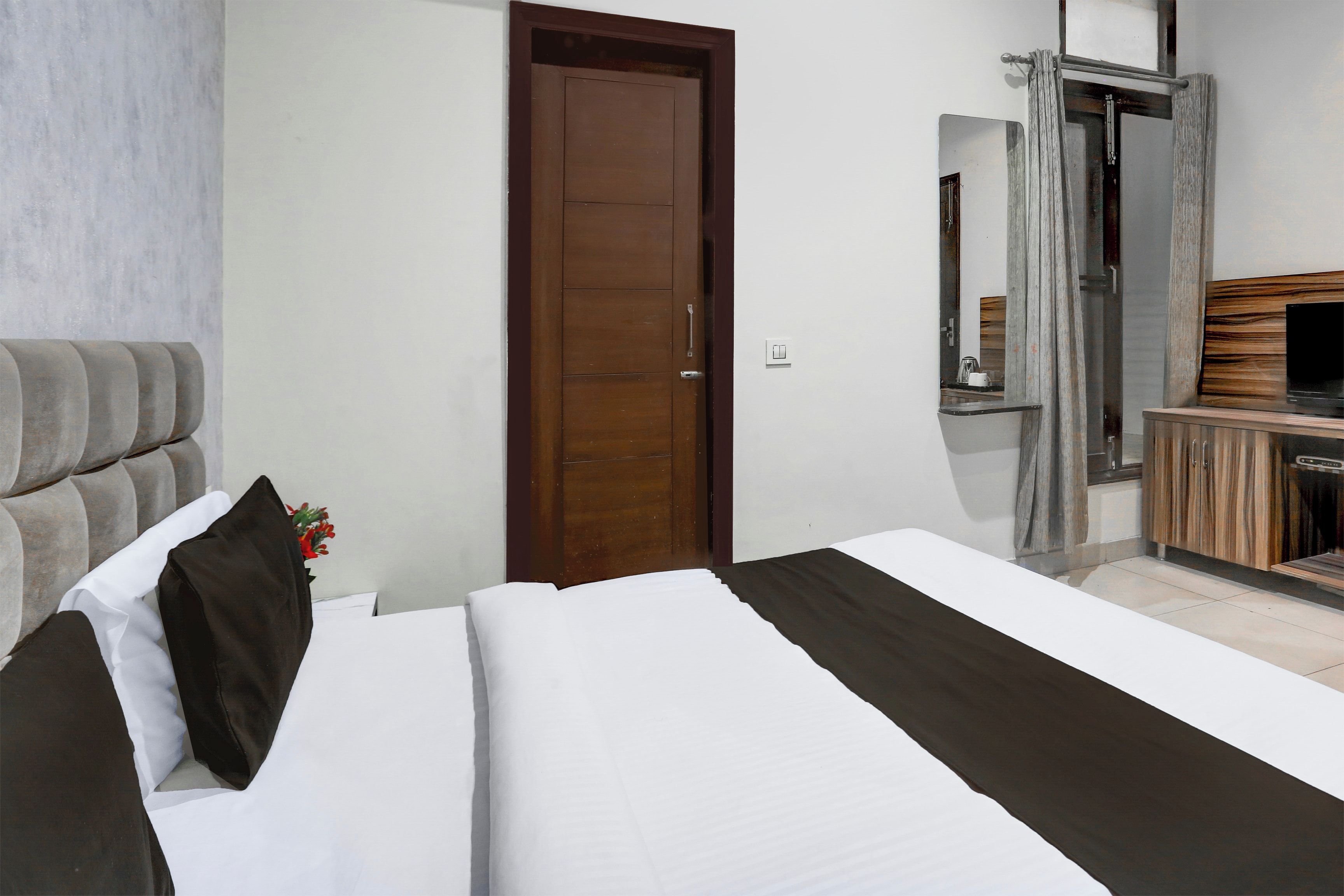 Habitación de hotel con cama, armario de madera, televisor y puerta del baño.