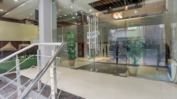 Un interior moderno con un separador de vidrio, barandales de metal y plantas en macetas.