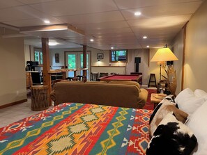 Ein Hotelzimmer mit Billardtisch, einer Couch, einem gemusterten Teppich und einem Hund.