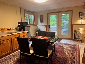 A kitchen with wooden cabinets, a microwave, and a refrigerator. There is a dining area with a table and chairs, and a rug on the floor. - Tranquil 3-bedroom house with AC in charming Conway (Conway)