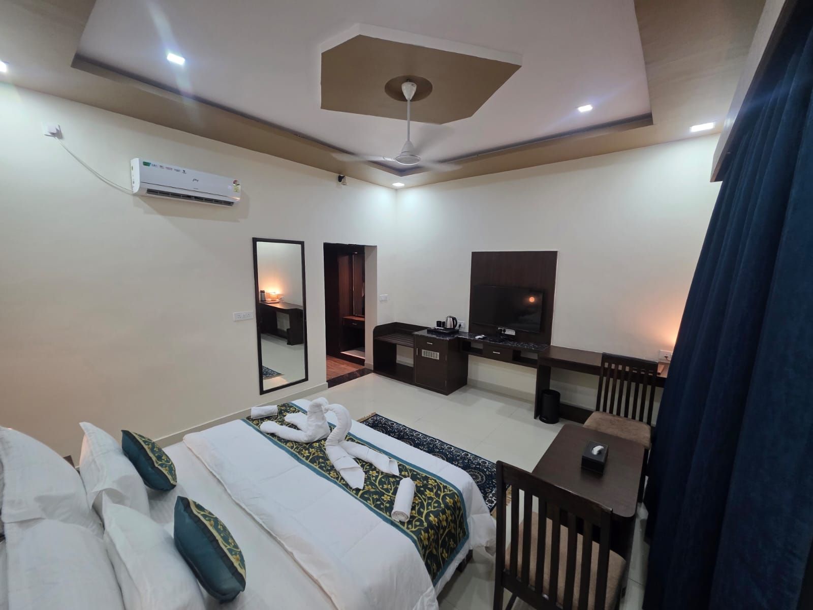 A hotel room with a bed, a desk, a television, and a ceiling fan.