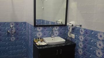 Un baño con un lavamanos blanco, un mueble negro y un espejo encima.
