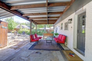 A covered patio with a stone floor, red chairs, a table, and a bench. - Recently Remodeled Dtwn Frisco Home w/ Yard! (Frisco)