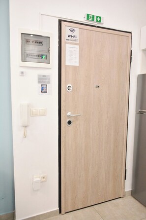 A wooden door with a Wi-Fi sign, a phone, and a light switch on the wall. - Comfortable Central Studios with City Views in Thessaloniki (Thessaloniki)