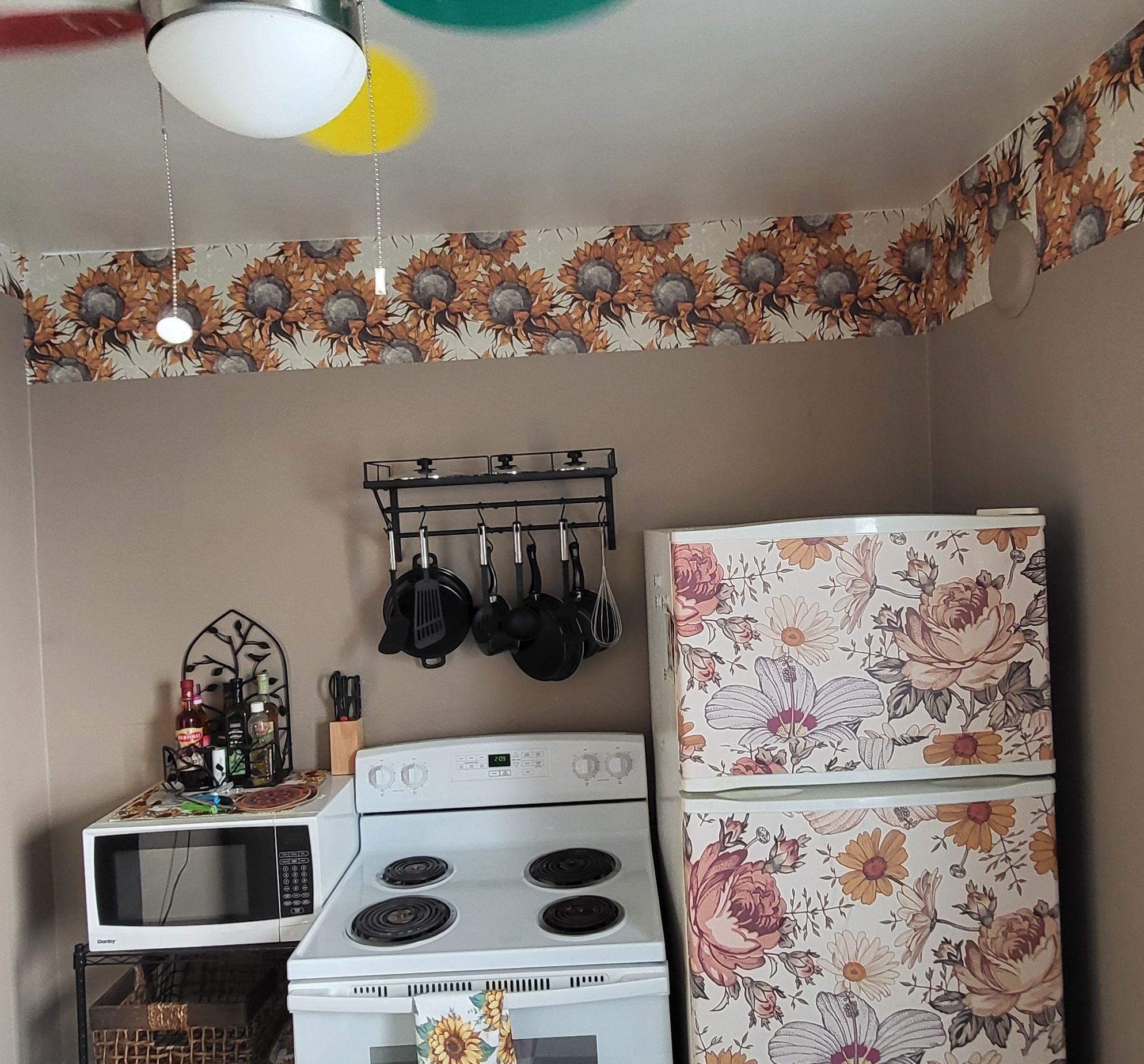 A kitchen with a white stove, a refrigerator with floral patterns, and hanging pots.