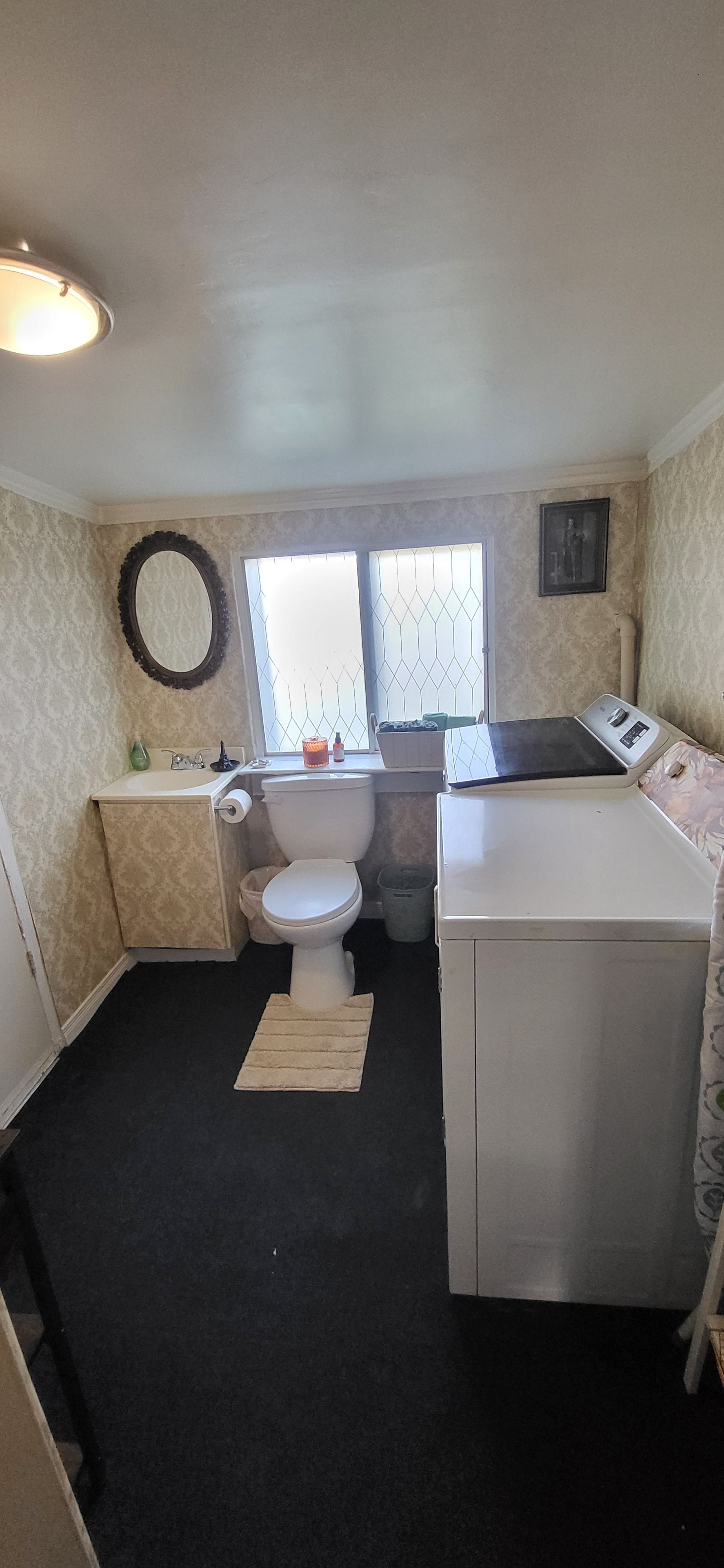 A compact bathroom with a toilet, sink, and a washing machine.