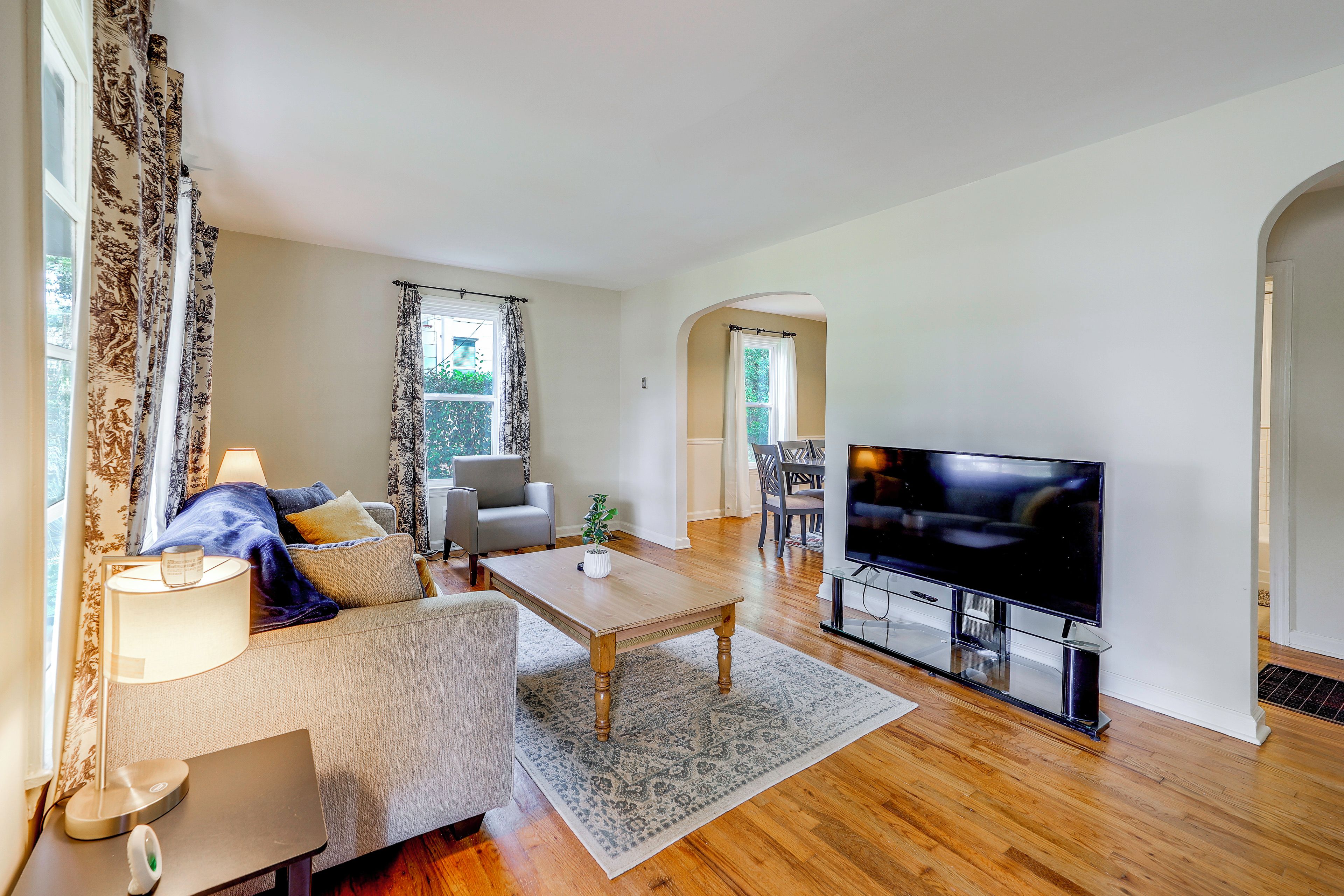 A living room with a sofa, coffee table, TV, and a dining area with chairs.
