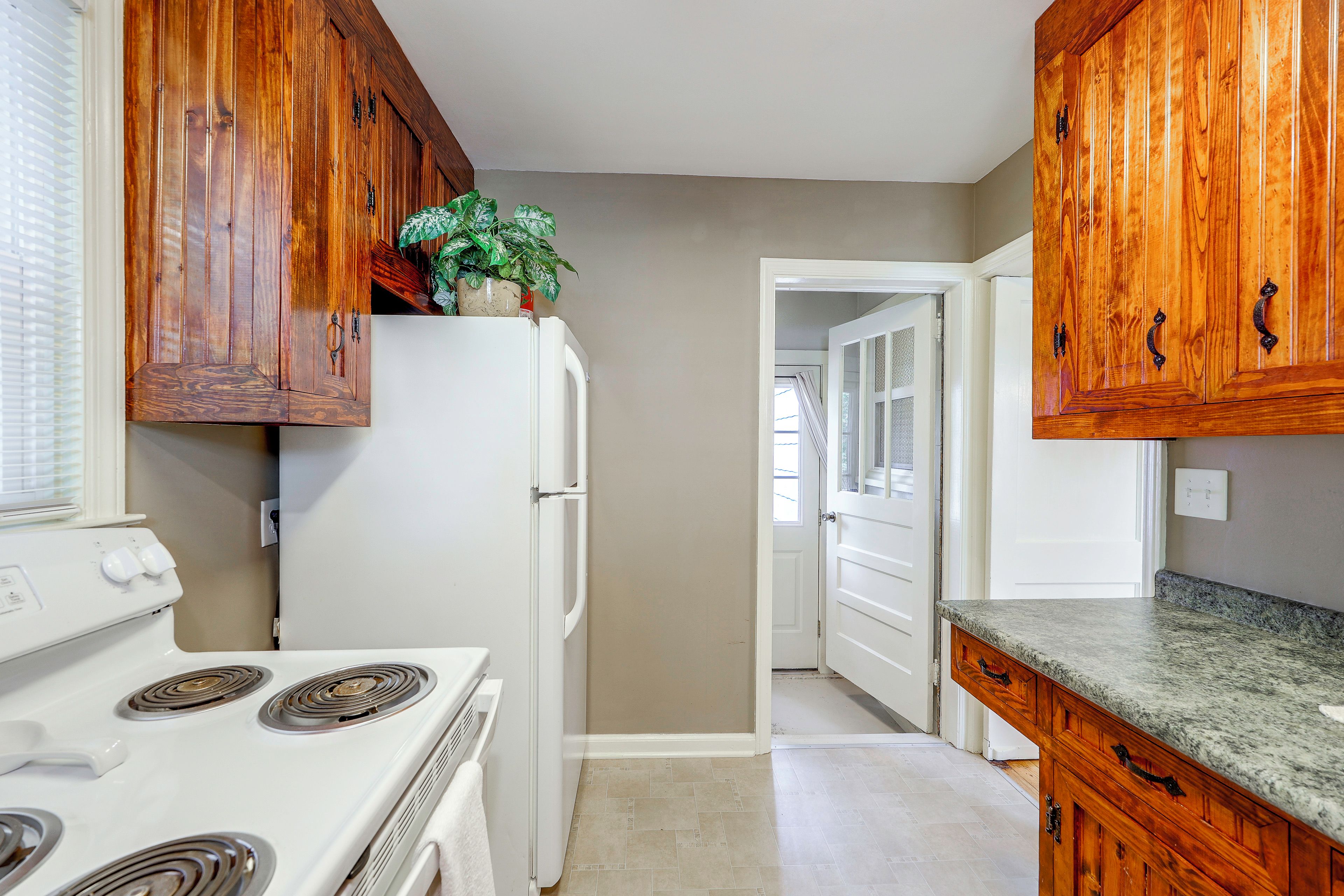 A kitchen with wooden cabinets, a white refrigerator, a stove, and a countertop.