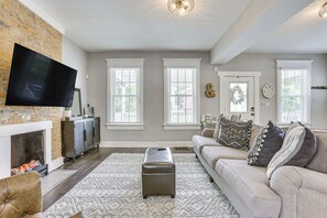 A spacious living room with a fireplace, a large flat-screen TV, and a comfortable sofa with decorative pillows.