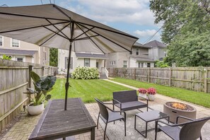 A patio area with a table, chairs, a fire pit, and a large umbrella.