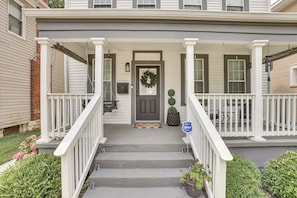 A two-story house with a front porch, a mailbox, and a door with a wreath.