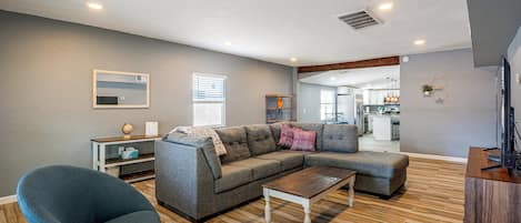 A modern living room with a sectional sofa, a coffee table, and a TV.