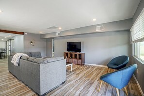 A modern living room with a grey sofa, a blue armchair, a flat-screen TV, and a wooden cabinet.